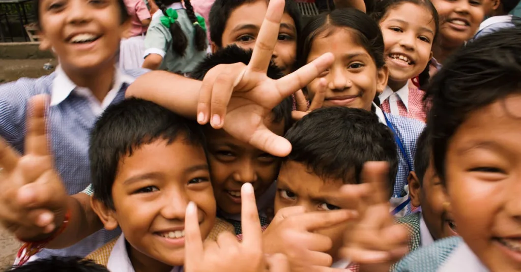 A joyful group of children smiling and making playful gestures outdoors in Namarjung, Nepal.